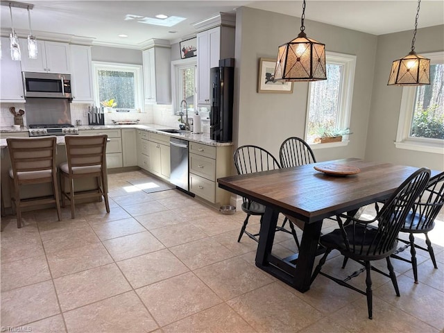 kitchen featuring tasteful backsplash, light stone counters, appliances with stainless steel finishes, pendant lighting, and a sink