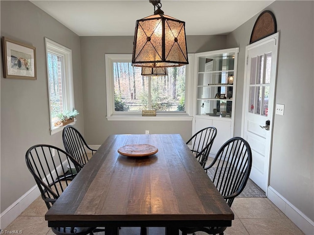 dining space featuring light tile patterned flooring, plenty of natural light, and baseboards