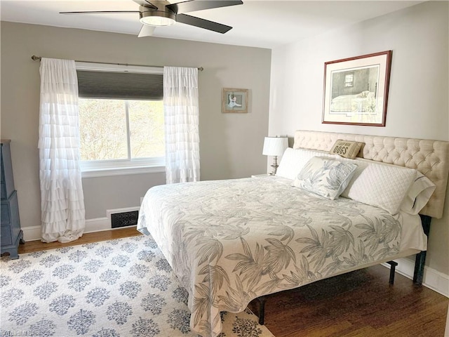 bedroom with a ceiling fan, wood finished floors, visible vents, and baseboards