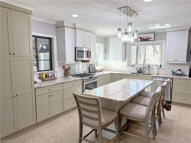 kitchen with hanging light fixtures, appliances with stainless steel finishes, a kitchen island, a sink, and a kitchen breakfast bar