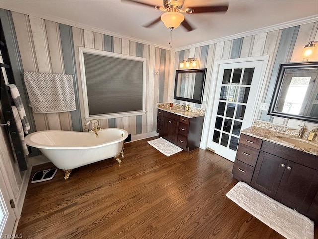 full bathroom with visible vents, wood finished floors, a sink, a freestanding bath, and two vanities