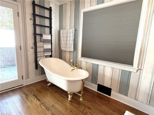 bathroom featuring a freestanding bath and wood finished floors