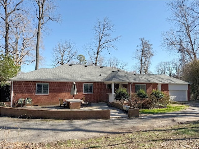 exterior space featuring brick siding, a patio, driveway, and an attached garage