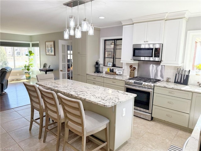 kitchen with stainless steel appliances, a center island, decorative backsplash, and light stone countertops