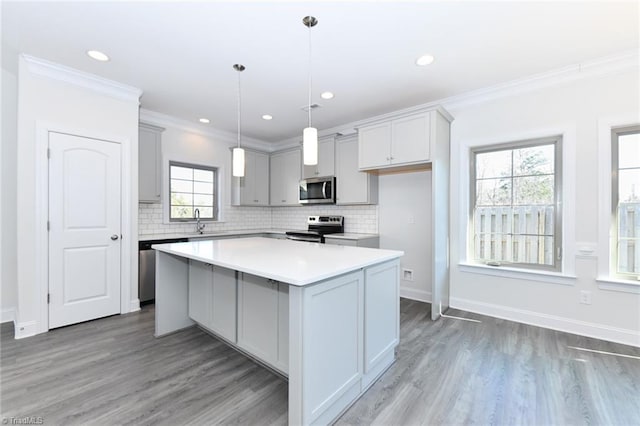 kitchen with stainless steel appliances, a wealth of natural light, gray cabinetry, and a center island