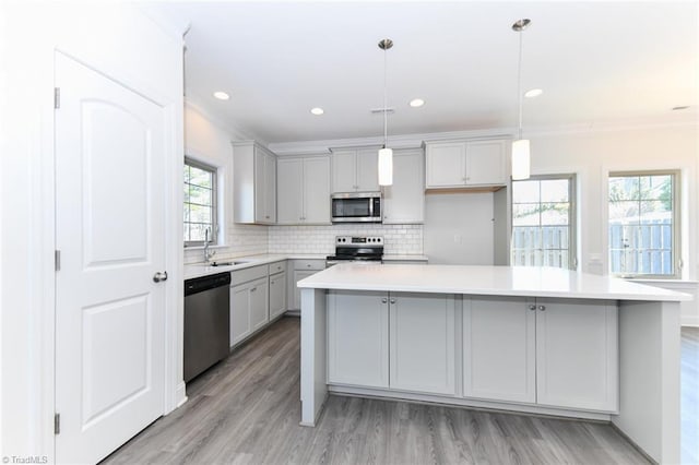 kitchen featuring appliances with stainless steel finishes, gray cabinetry, a center island, pendant lighting, and sink