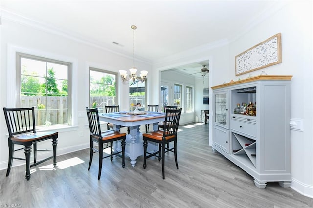 dining area with ceiling fan with notable chandelier, wood-type flooring, and crown molding