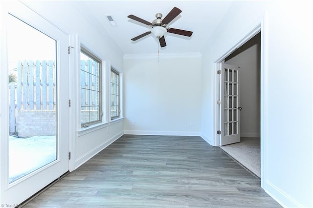 interior space with wood-type flooring, ceiling fan, french doors, and ornamental molding