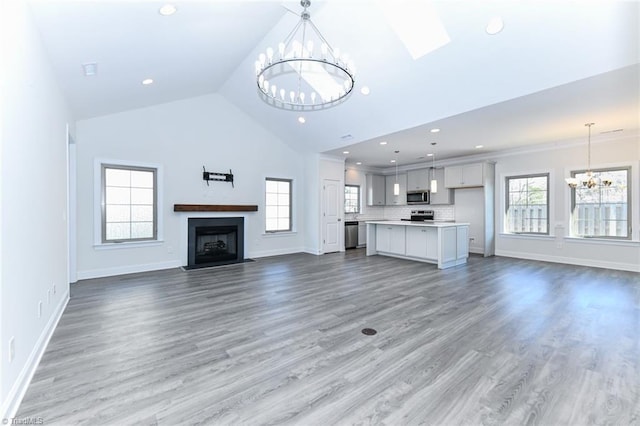 unfurnished living room featuring a notable chandelier, ornamental molding, high vaulted ceiling, and hardwood / wood-style flooring