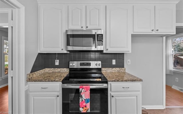 kitchen featuring visible vents, backsplash, dark stone counters, stainless steel appliances, and white cabinetry