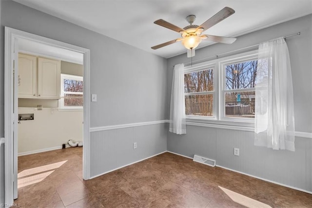 spare room with visible vents, wainscoting, and a ceiling fan