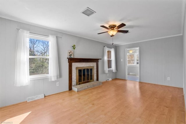 unfurnished living room featuring visible vents, crown molding, a fireplace, wood finished floors, and a ceiling fan