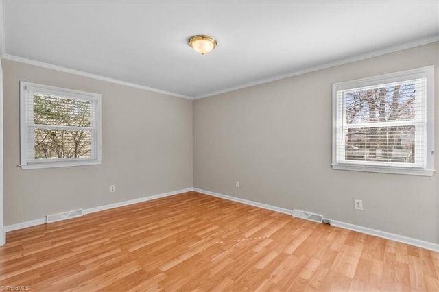 unfurnished room featuring plenty of natural light, crown molding, light wood-type flooring, and baseboards