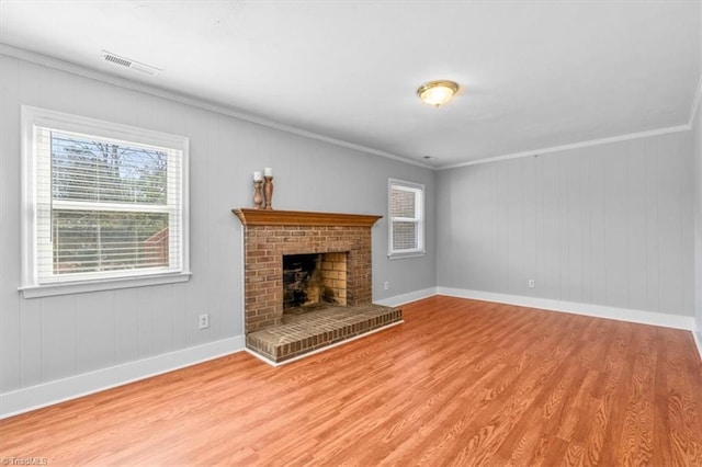 unfurnished living room featuring wood finished floors, baseboards, visible vents, a fireplace, and ornamental molding