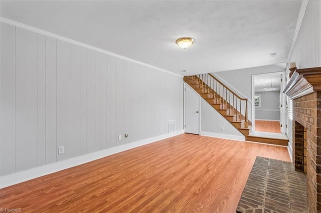 unfurnished living room featuring visible vents, a fireplace, crown molding, and wood finished floors