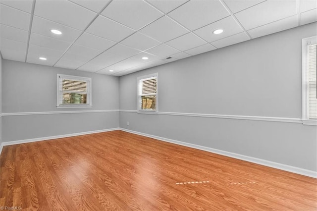 below grade area with a paneled ceiling, baseboards, and wood finished floors