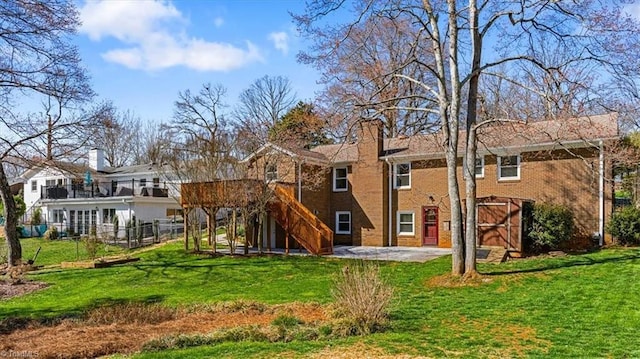 rear view of house with fence, stairs, a chimney, a yard, and a patio area