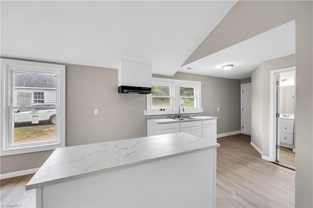 kitchen featuring white cabinetry, sink, light hardwood / wood-style floors, and vaulted ceiling