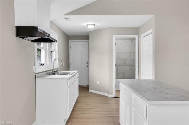 kitchen with sink, white cabinets, wall chimney range hood, and light hardwood / wood-style flooring