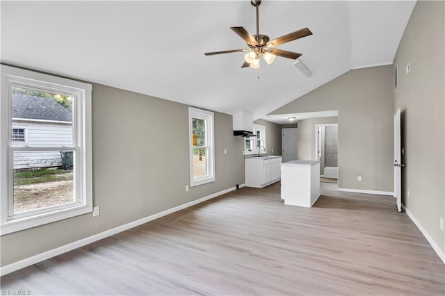 unfurnished living room featuring ceiling fan, sink, light hardwood / wood-style flooring, and vaulted ceiling