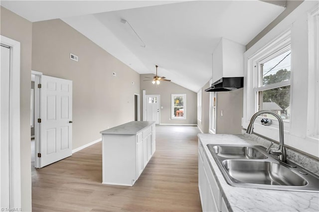 kitchen with sink, white cabinets, a center island, light hardwood / wood-style floors, and lofted ceiling