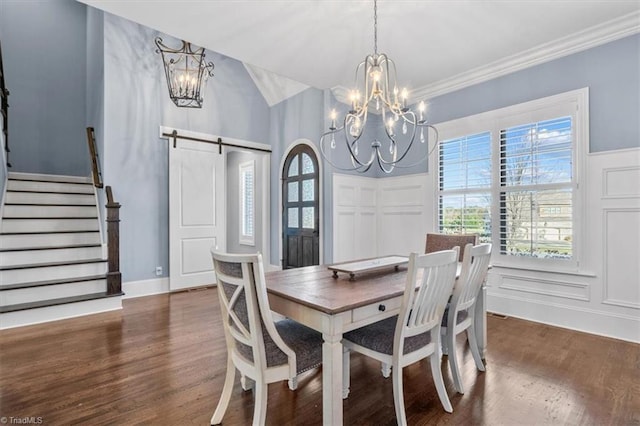 dining room with dark wood-type flooring, an inviting chandelier, a barn door, crown molding, and lofted ceiling