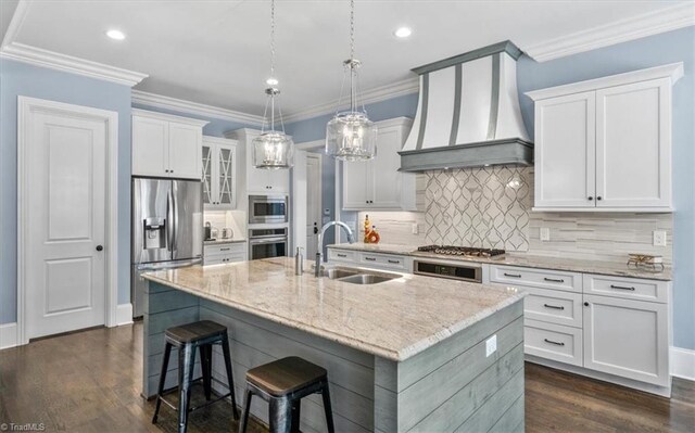 kitchen featuring custom range hood, sink, stainless steel appliances, and a center island with sink