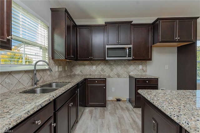 kitchen with sink, decorative backsplash, light stone counters, dark brown cabinets, and light wood-type flooring