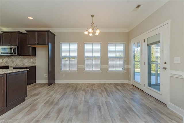 kitchen featuring dark brown cabinetry, light stone counters, tasteful backsplash, and a healthy amount of sunlight