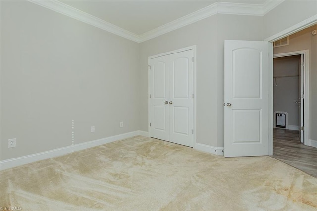 unfurnished bedroom featuring ornamental molding, light colored carpet, and a closet