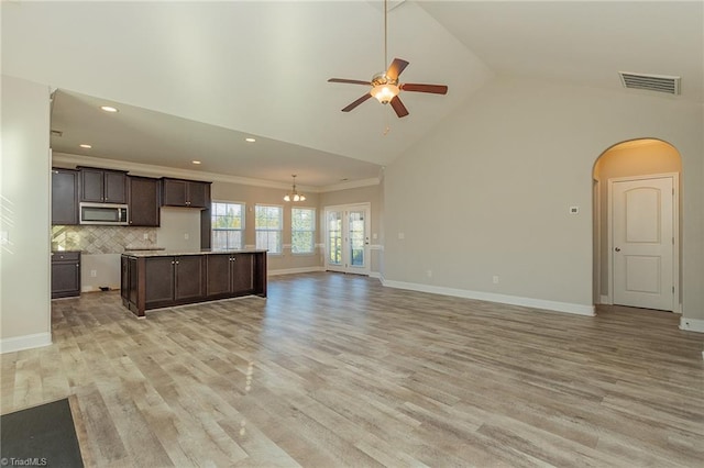 kitchen featuring ceiling fan, dark brown cabinets, a center island, decorative backsplash, and light wood-type flooring