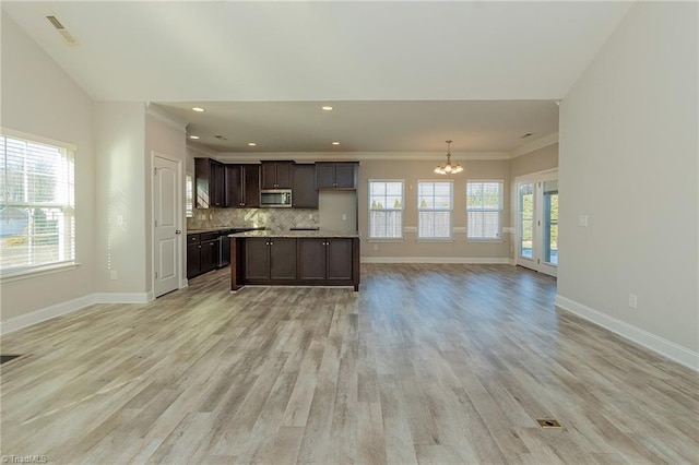 kitchen with tasteful backsplash, hanging light fixtures, dark brown cabinetry, an inviting chandelier, and light hardwood / wood-style flooring