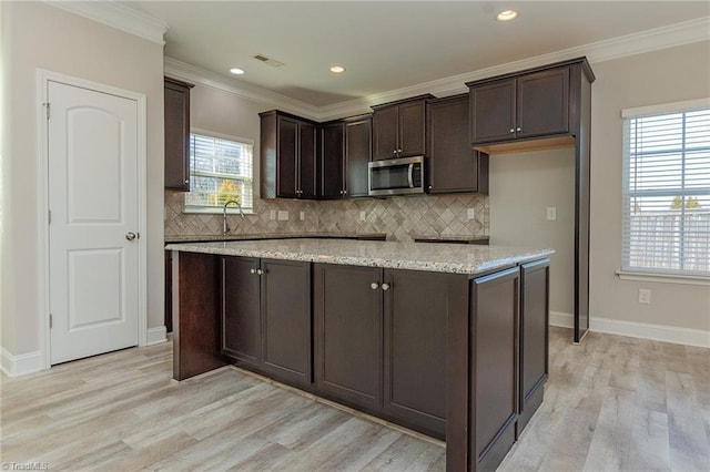 kitchen featuring crown molding, decorative backsplash, and light wood-type flooring