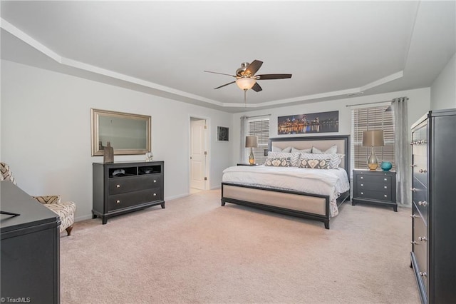 bedroom with light carpet, a ceiling fan, a raised ceiling, and baseboards