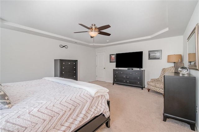 bedroom featuring light colored carpet, a ceiling fan, and a tray ceiling