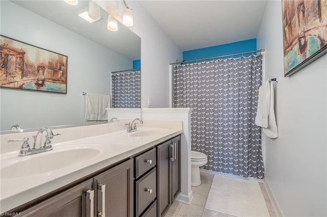 full bath with a sink, toilet, double vanity, and tile patterned floors