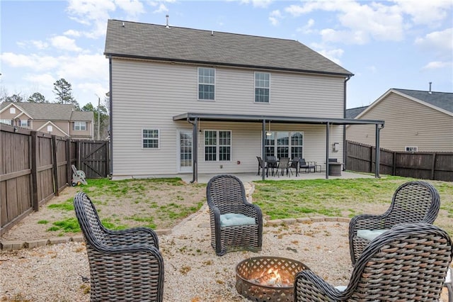 rear view of house featuring a gate, a yard, a fenced backyard, a fire pit, and a patio area