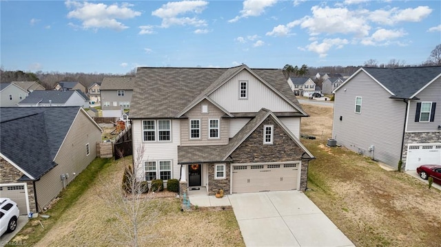 view of front of property featuring roof with shingles, concrete driveway, a garage, stone siding, and a residential view