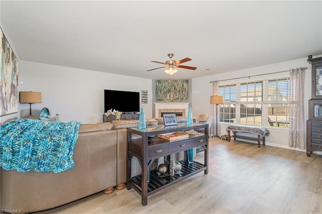 living room featuring a fireplace, wood finished floors, and a ceiling fan