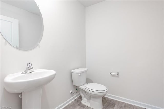 bathroom with hardwood / wood-style flooring, toilet, and sink