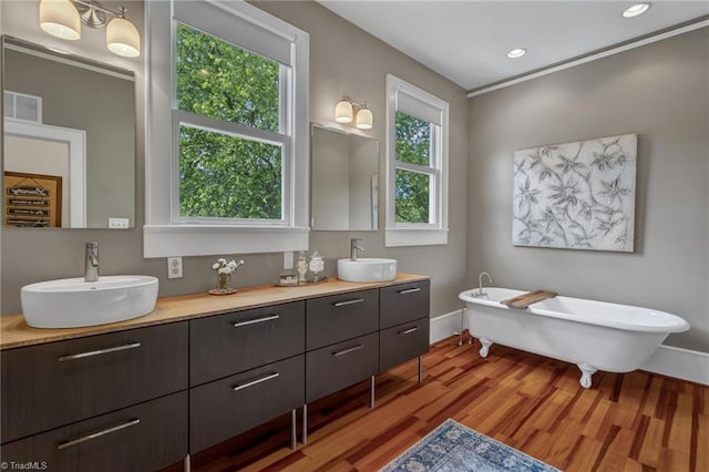 638 N Spring St, Winston-Salem, NC 27101 - bathroom featuring double vanity, a freestanding bath, wood finished floors, baseboards, and recessed lighting
