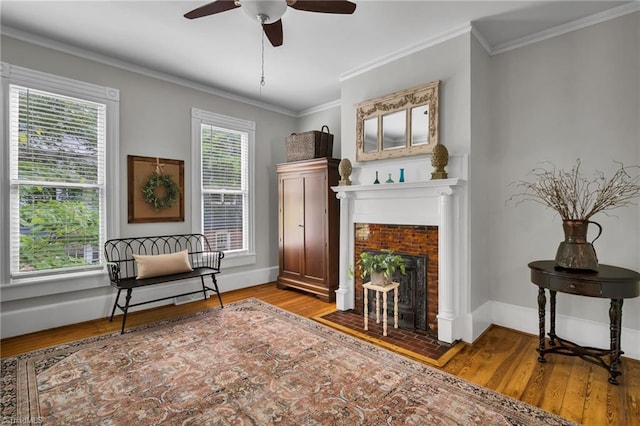 638 N Spring St, Winston-Salem, NC 27101 - sitting room featuring wood finished floors, a ceiling fan, crown molding, baseboards, and a fireplace with flush hearth