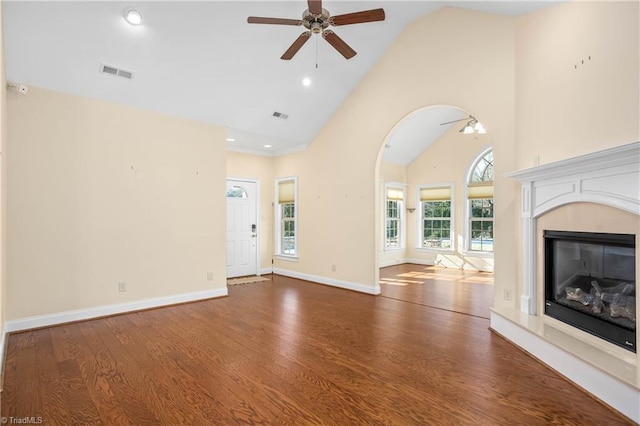 unfurnished living room with ceiling fan, a premium fireplace, high vaulted ceiling, and wood-type flooring