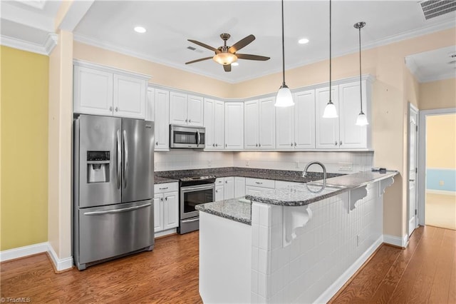 kitchen with stainless steel appliances, white cabinetry, a breakfast bar area, and kitchen peninsula