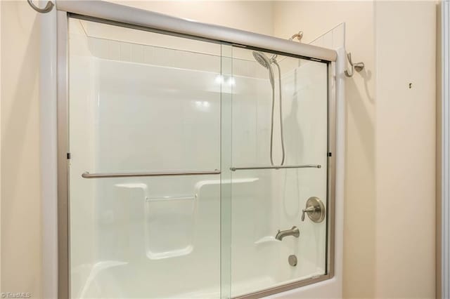 bathroom featuring combined bath / shower with glass door