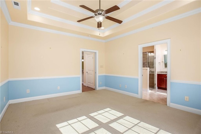 carpeted empty room with ornamental molding, ceiling fan, and a raised ceiling