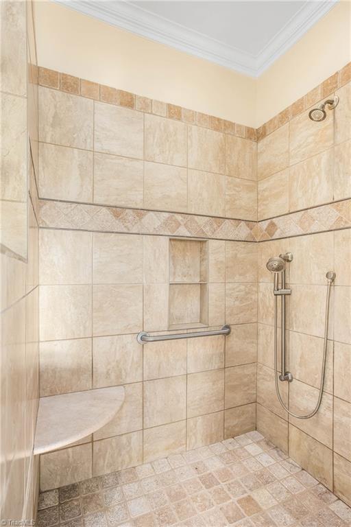 bathroom with tiled shower and crown molding