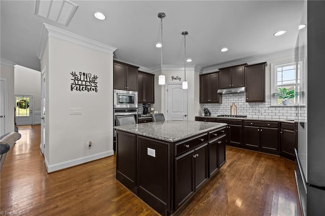 2590 Mccullum Ct, Browns Summit, NC 27214 - kitchen featuring appliances with stainless steel finishes, crown molding, a center island, decorative backsplash, and light stone counters