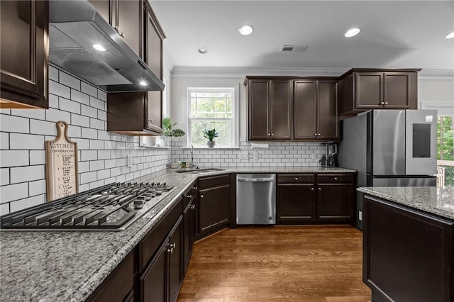 2590 Mccullum Ct, Browns Summit, NC 27214 - kitchen with appliances with stainless steel finishes, extractor fan, ornamental molding, light stone countertops, and dark brown cabinets