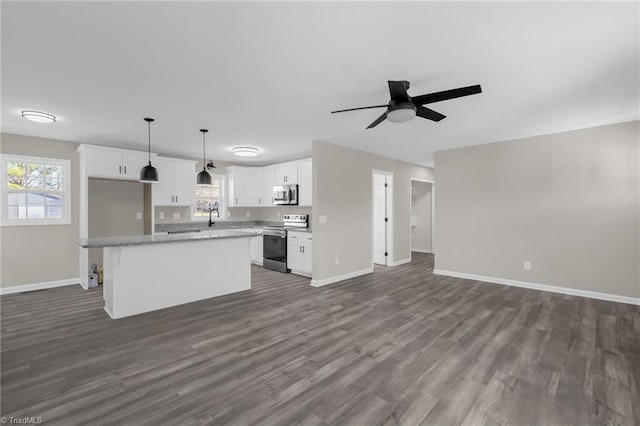 kitchen featuring appliances with stainless steel finishes, a kitchen island, decorative light fixtures, white cabinetry, and a healthy amount of sunlight